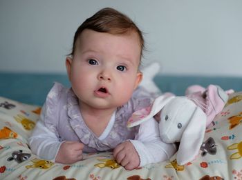 Portrait of cute baby girl lying on bed at home