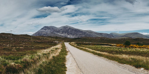 Road amidst field against sky