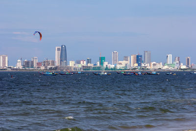 Sea by buildings against sky in city