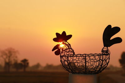 Close-up of silhouette metal against orange sky