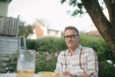 Portrait of smiling senior man sitting at table in backyard