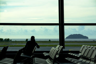 Rear view of man sitting in waiting room at airport