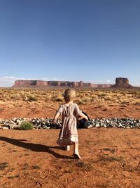 Rear view of woman on field against clear sky