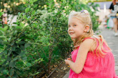 Portrait of young woman standing against plants