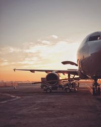 Airplane on runway against sky during sunset