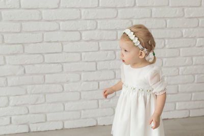 Side view of girl standing against brick wall