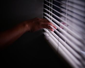 Cropped hand on blinds at home