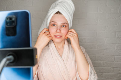 Woman doing spa procedure mud mask at home online.