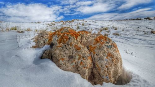 Snow covered landscape against cloudy sky