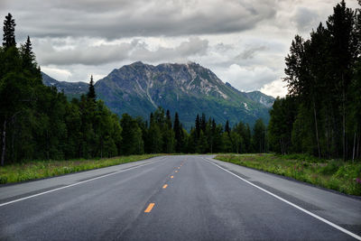 Road by trees against sky