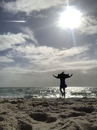 Silhouette woman on beach against sky