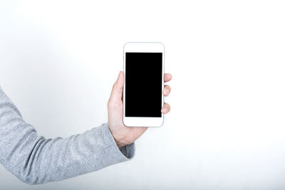 Low section of person holding smart phone over white background