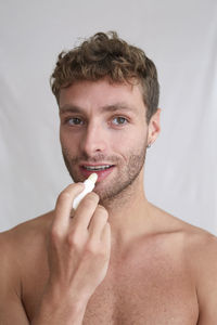 Portrait of handsome young man holding cigarette over white background