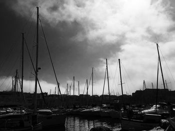 Sailboats moored at harbor against sky