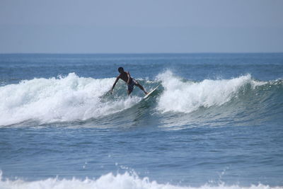 Man surfing in sea against sky