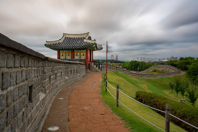 Footpath leading towards historic temple against sky