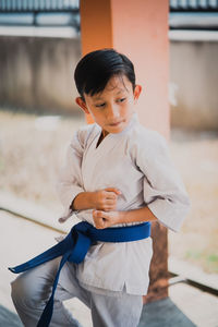 Boy holding camera while standing outdoors