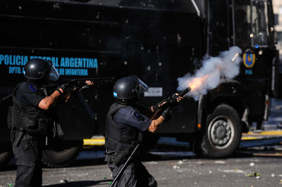 Police officers firing on street during riots in city