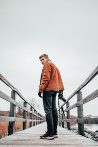 Full length of man standing on railing against sky