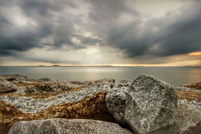 Rocks by sea against sky during sunset