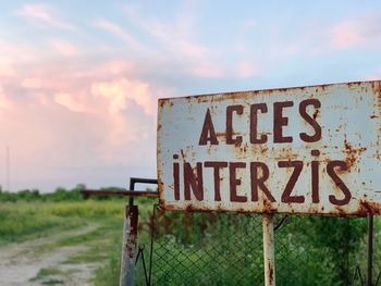 Information sign on fence against sky