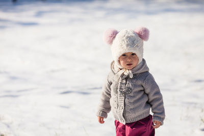 Cute boy standing on snow covered land