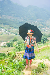 Woman with umbrella standing on landscape