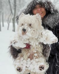 Smiling woman with dog standing outdoors during snowfall