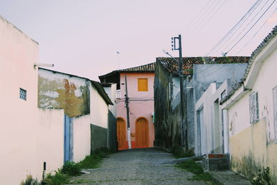 Alley amidst houses against sky