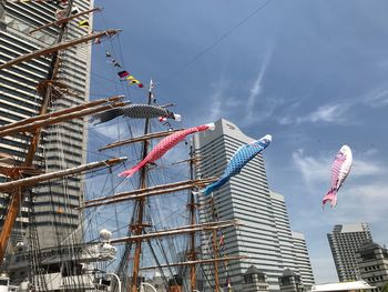 Low angle view of crane by building against sky