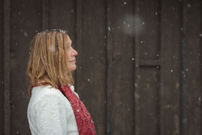 Young woman looking away while standing on snow