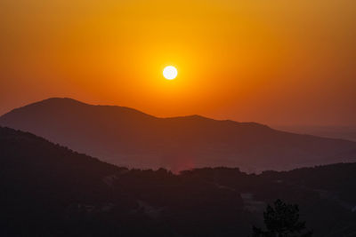 Scenic view of silhouette mountains against romantic sky at sunset