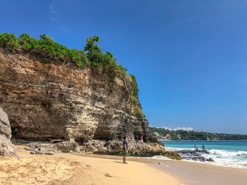 Rock formation on beach against blue sky