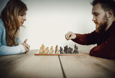 Couple playing chess on table at home