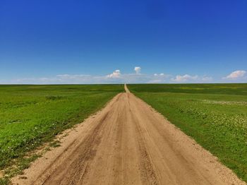 Road amidst field against sky