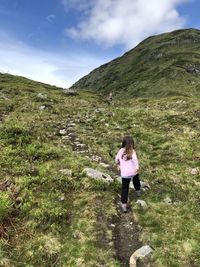 Rear view of woman hiking on mountain against sky