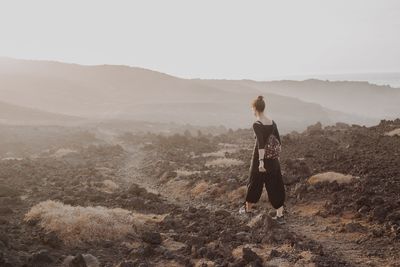 Rear view of woman looking at mountains against sky