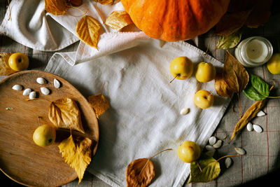 There is a layout of pumpkin and autumn leaves on the kitchen table