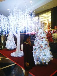 Woman standing on illuminated christmas tree