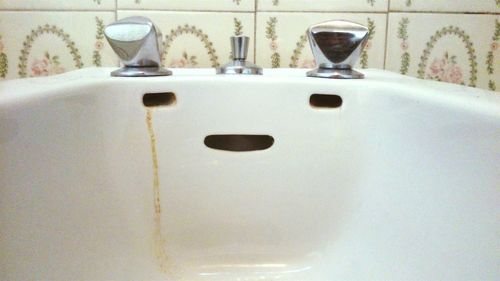 Stained anthropomorphic face on bathroom sink at home