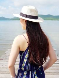 Rear view of woman standing on jetty looking at lake