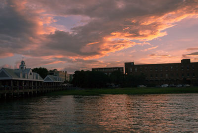 River by buildings against sky during sunset