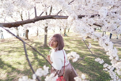 Woman standing by cherry blossom