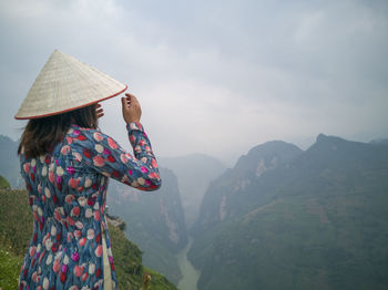 Rear view of woman looking at mountains against sky