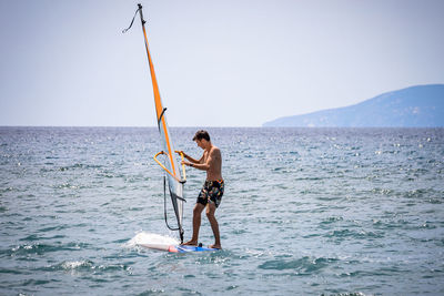 Full length of man fishing in sea against clear sky