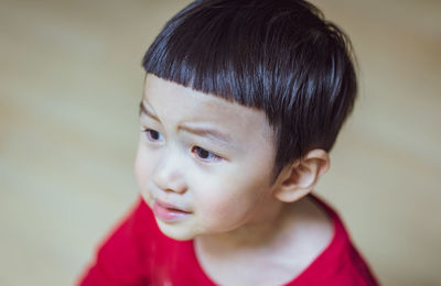 Close up of little caucasian boy in a red t-shirt and bangs hairstyle feel upset,angry. 