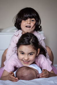 Pyramid of three smiling kids lying on each other