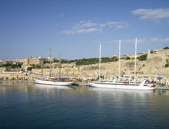 Boats moored at harbor against sky