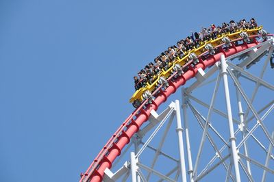 Low angle view of roller coaster against clear blue sky