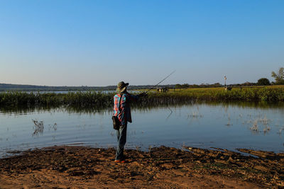 Man standing in lake against clear sky